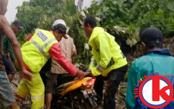 Warga saat membantu pengendara motor melintas di lokasi longsor