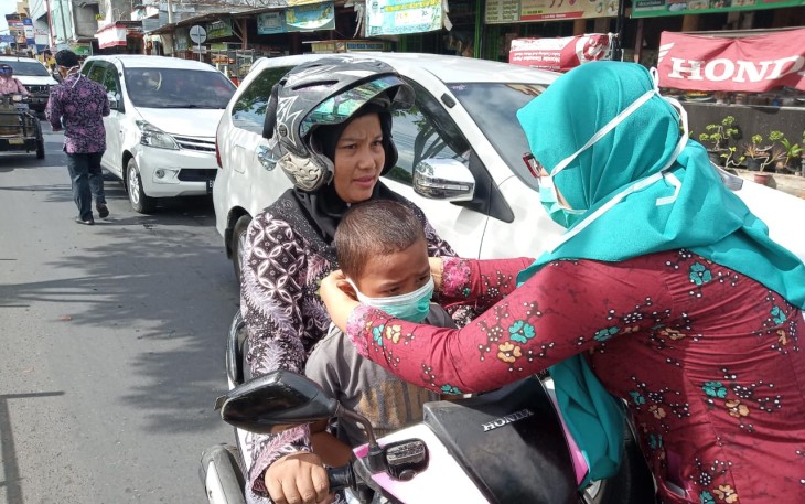 Seorang relawan membagikan masker gratis bagi pengendara sepeda motor