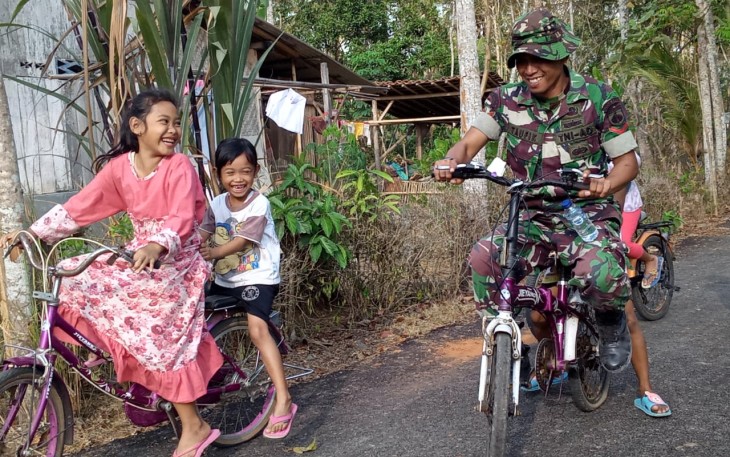 Anak-anak bersepeda bersama salah satu anggota TNI