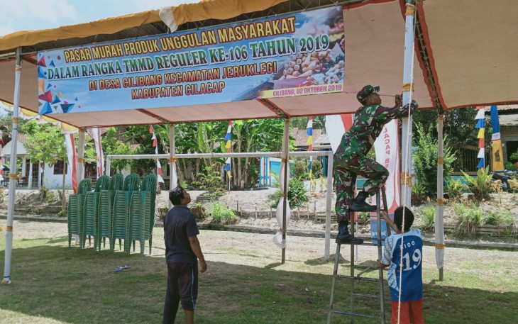 Kopda Taufik Bantu Stan Warga Dalam Pasang Banner Pasar Murah Produk Unggulan Masyarakat Desa Cilibang