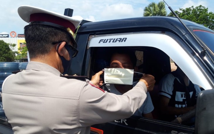 Salah satu personel Ditlantas Polda Kepri memakaikan Masker kepada salah satu pengendara