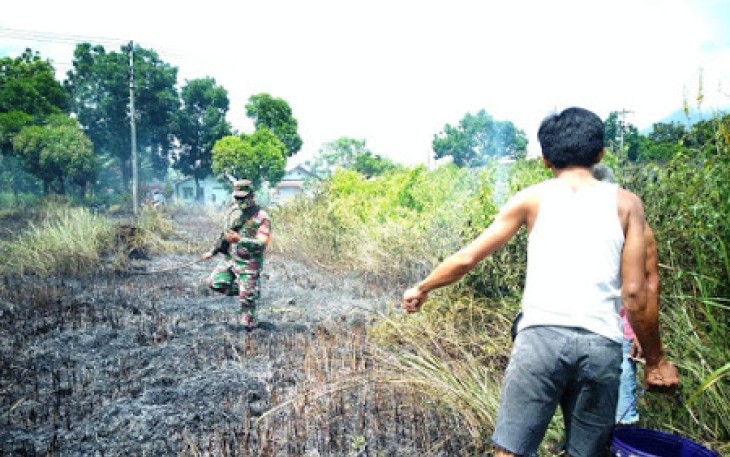 Babinsa Padamkan Kebakaran Hutan Ilalang di Kelurahan Manembo-Nembo