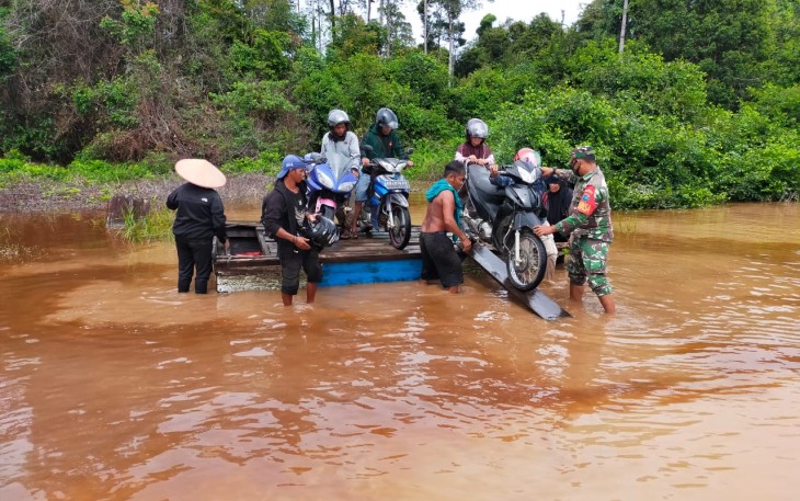 Babinsa Bantu Seberangkan Motor dan Warga yang Melintas