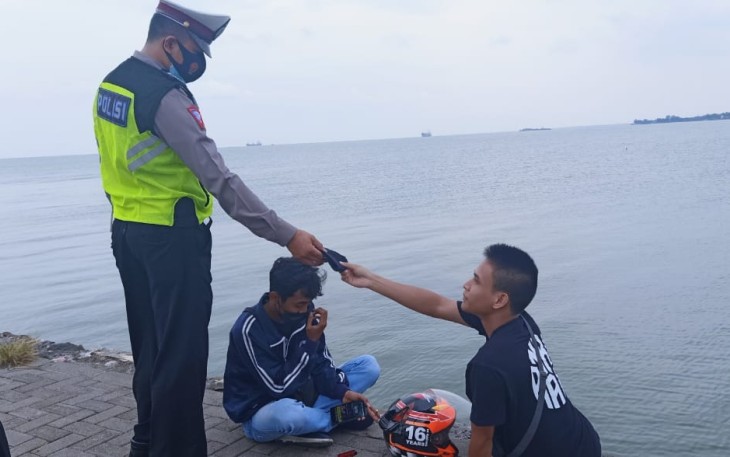 Anggota Satlantas Polres Kendal memberikan masker gratis kepada salah satu pengunjung Pelabuhan Kendal, Jum'at 22/10/2021