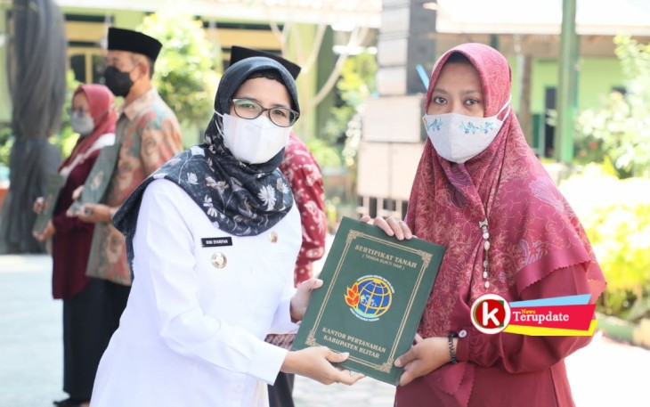 Bupati Rini (kiri) Bagikan Sertipikat PTSL ke Warga Bakung, Udanawu. (foto : Faisal NR / Klikwarta.com)
