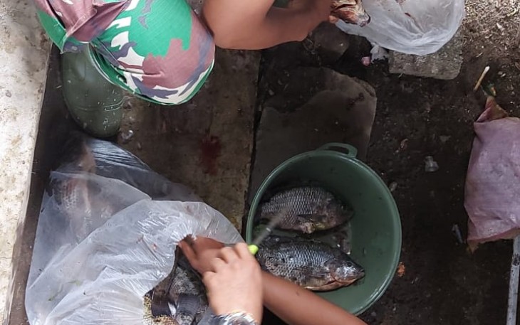 Personil satgas TMMD ke 111 kodim 1310/Bitung saat bantu warga bersihkan ikan