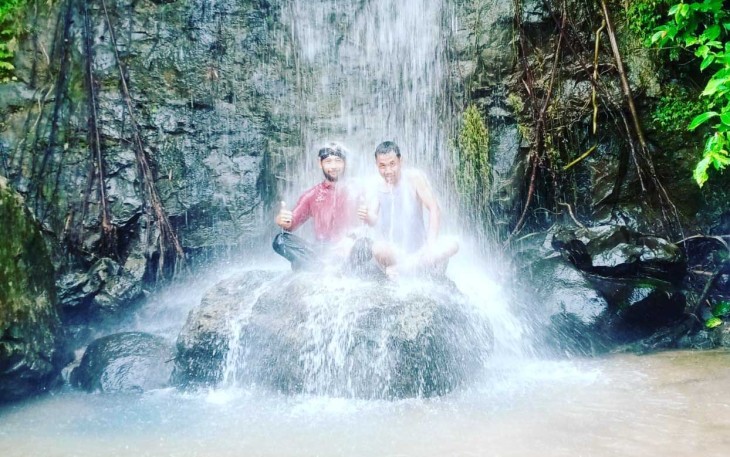 Kades Tanjung Kuaw dan salah satu anggota Tim Trip Klikwarta.com saat berada di bawah air terjun. Foto: Istimewa/Doc.klikwarta.com