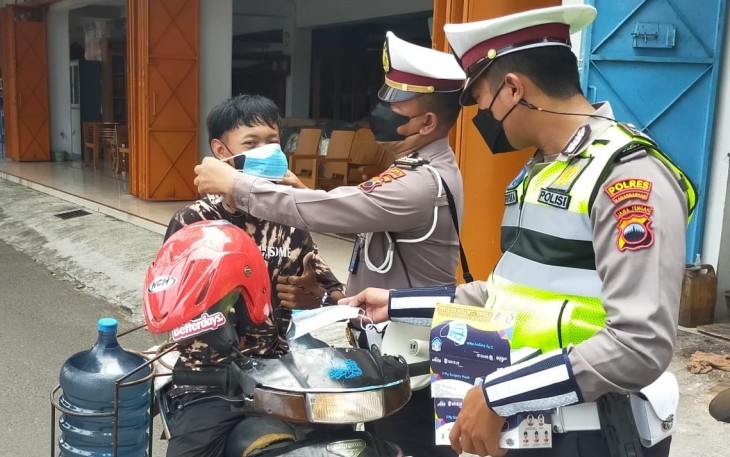 Personil Satlantas Polres Karanganyar saat membagikan masker gratis di  kawasan simpang empat Jalan Lawu, Papahan, Tasikmadu, Karanganyar, Kamis (3/2/2022)
