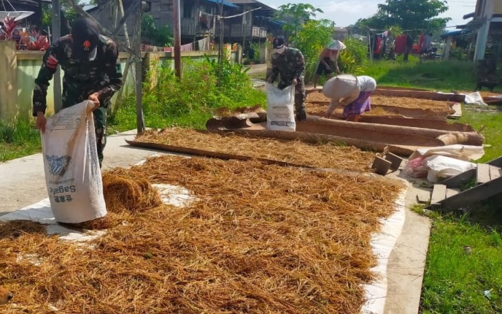 Anggota Satgas Yonif 144/JY Bantu Warga Menjemur Padi di Perbatasan