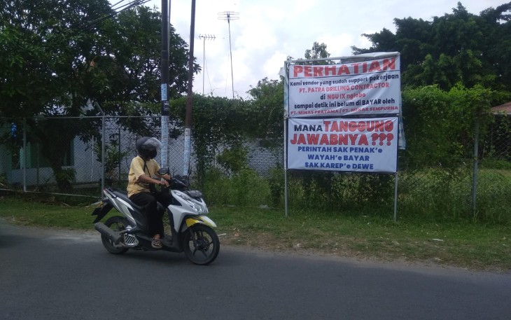Banner bertuliskan protes kepada PT Minas/Mekar Sampurna yang dipasang vendor lokal di sekitar lokasi lapangan atletik Cepu