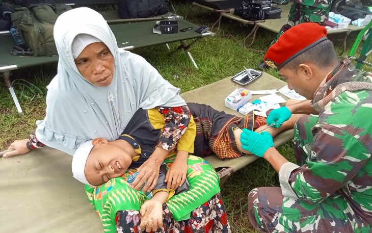 Prajurit Kopassus saat mengobati luka anak korban 