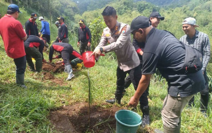 Kapolres Batu AKBP Oskar Syamsuddin saat menyiram bibit pohon pinus