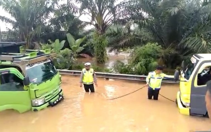 Petugas saat berupaya mengevakuasi truk terjebak banjir