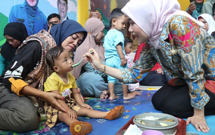 Hafizha menyuapi Rantang Sehat (aneka makanan penuh gizi) kepada anak-anak Balita dan Baduta