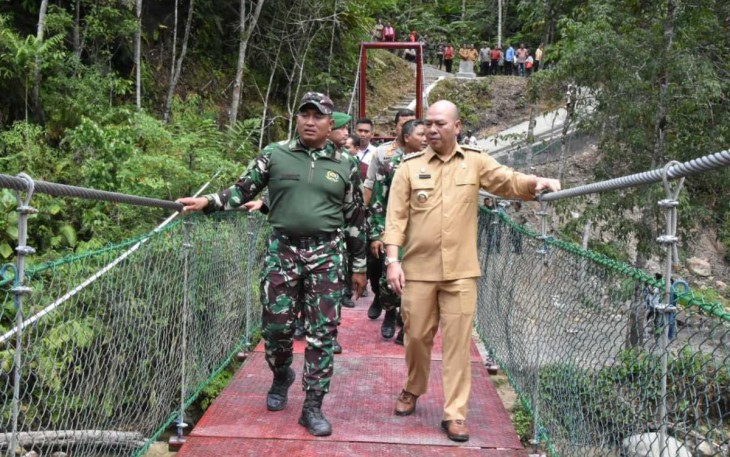 Danrem 023/KS Kolonel Inf Lukman Hakim bersama Bupati Tapanuli Utara Nikson Nababan saat melintasi jembatan gantung usai peresmian, Selasa (18/7)