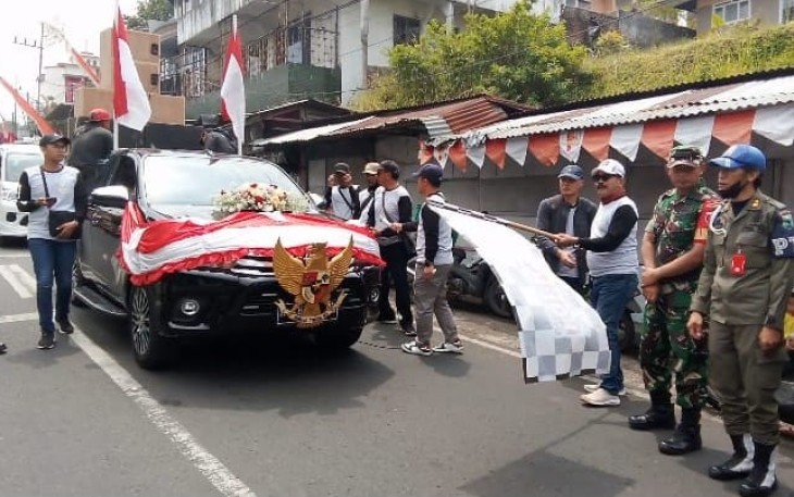 Kades Punten Hening Trisunu, saat memberangkatkan para peserta karnaval dengan mengibarkan bendera, Senin (21/8)