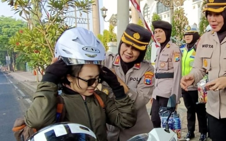 Polwan Polda Jatim saat memberikan helm gratis jelang HUT Polwan ke 75, Kamis (31/8)
