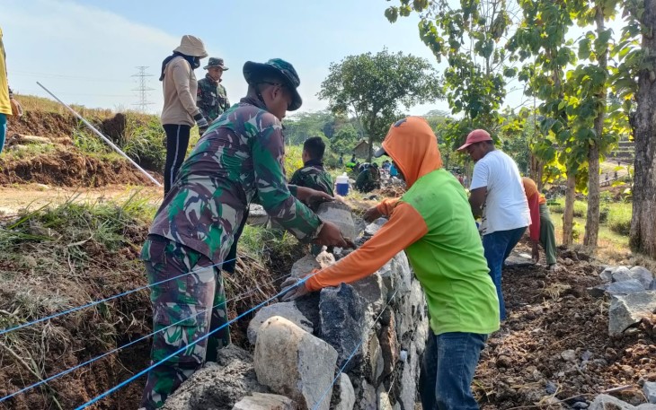 "Satgas TMMD Reg ke-117 Mojogedang sedang memasang talud pembats kanan-kiri jalan bersama warga"