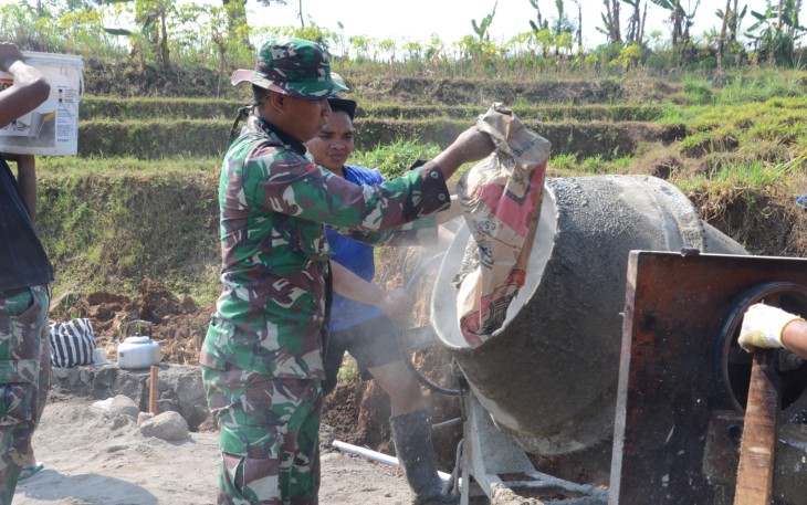 "Anggota Satgas TMMD sedang menyiapkan adukan semen"