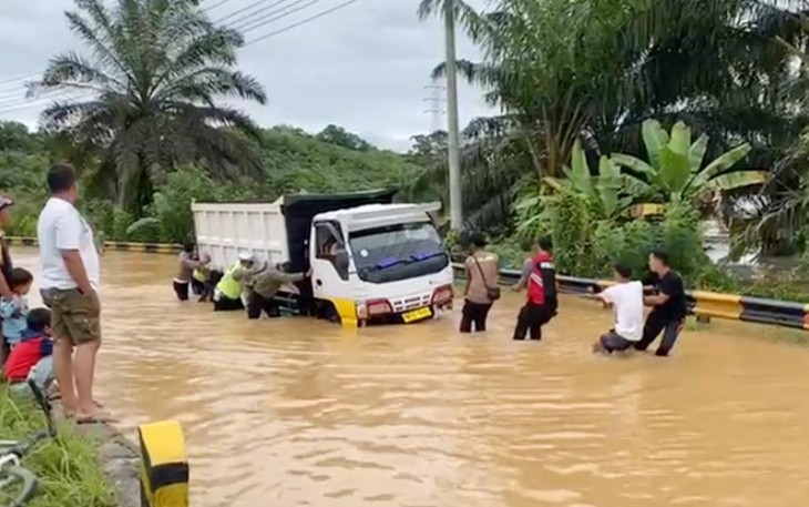 Polisi bersama Warga saat Lakukan Evakuasi Truk Terjebak Banjir