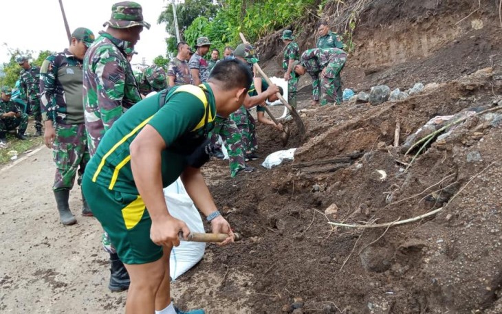 Personil kodim 1310/Bitung bersama warga saat membersihkan jalan yang tertimpa tanah longsor
