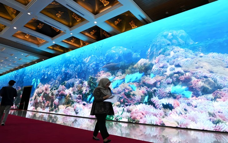 Seorang perempuan berjalan melewati monitor yang menampilkan ekosistem laut di venue HLM AIS Forum 2023 di Bali Nusa Dua Convention Center, Kabupaten Badung, Bali, Senin (9/10/2023). Monitor berukuran panjang 79 meter dan tinggi 6 meter yang menampilkan animasi ekosistem bawah air karya animator lokal ini akan menyambut kedatangan delegasi HLM AIS Forum 2023 di venue. Media Center HLM AIS Forum 2023/Akbar Nugroho Gumay/pras/ratih.