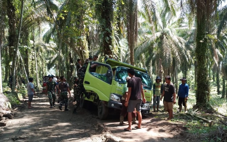 Satgas TMMD dan warga mengevakuasi Truk yang terperosok di badan jalan. 