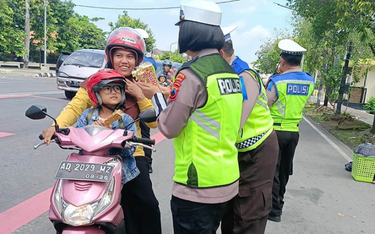 Anggota Satlantas Polres Karanganyar sedang memberikan cokelat dan bunga kepada pengendara sepeda motor, Senin (4/3/2024).