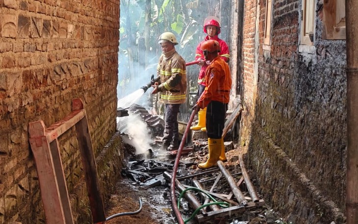Petugas melakukan proses pendinginan di lokasi kebakaran rumah milik Erna (30), di Dusun Tirto RT 01 RW 12, Bolong, Karanganyar, Kamis pagi (9/7/2026)