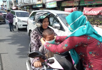 Seorang relawan membagikan masker gratis bagi pengendara sepeda motor