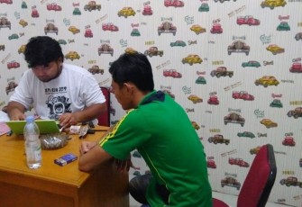 Tersangka mengenakan kaos hijau saat diperiksa penyidik