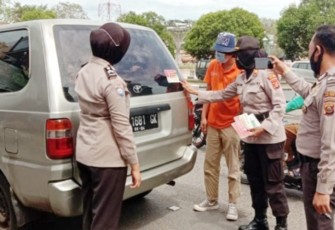 Personel Polres OKU Timur memberikan imbauan sekaligus pasang stiker di mobil pengendara yang melintas