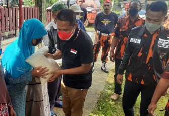  Anggota Komisi VIII DPR RI Paryono didampingi Ketua MPC Pemuda Pancasila Disa Agen Alifven sedang  menyerahkan bantuan sembako kepada warga kurang mampu di Desa Ngargoyoso, Kecamatan Ngargoyoso, Kabupaten Karanganyar, Jawa Tengah, pada Sabtu (18/12/2021)
