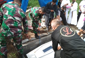 Sejumlah personel satgas TMMD kodim Bitung saat bantu turunkan peti jenazah