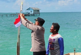 Kapolsek saat membagikan bendera merah putih diatas pompong milik nelayan