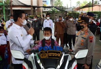 Usai divaksin, anak-anak berfoto di atas kendaraan dinas Polisi