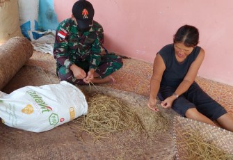Anggota Satgas Yonif 144/JY Bantu Warga Bersihkan Gabah Padi 