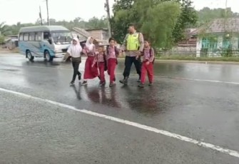 Polisi saat membantu anak-anak menyebrang jalan.