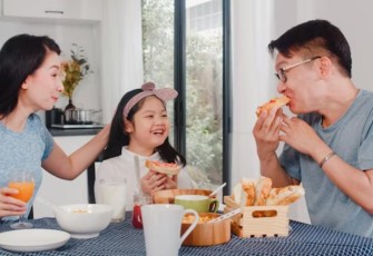 Ilustrasi. Foto: Asian mom, dad, and daughter feeling happy talking together while eating. (Sumber: medcom.id)