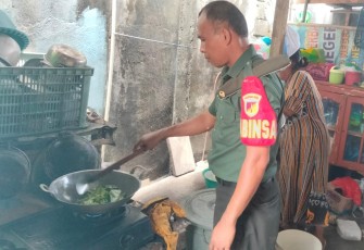 Babinsa Jajaran Kodim 1310/Bitung saat membantu warga menyiapkan makanan