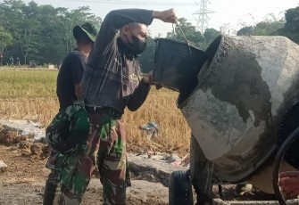 "Anggota Satgas TMMD sedang menuang bahan material ke dalam Molen pengaduk semen"