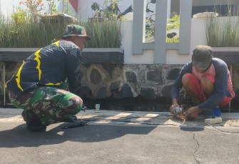 "Anggota Satgas TMMD sedang menganyam besi sloof bersama warga"