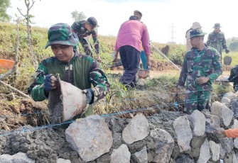 "Personel Satgas TMMD Reg ke-117 Mojogedang sedang mengerjakan pemasangan batu miring"