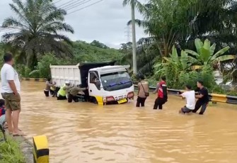 Polisi bersama Warga saat Lakukan Evakuasi Truk Terjebak Banjir