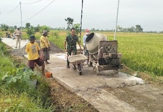 Babinsa Kaibon saat Bantu Masyarakat Rabat Jalan di Area Persawahan