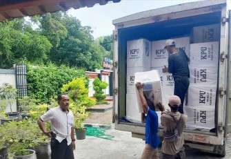 Pekerja sedang mengangkat kotak logistik Pemilu 2024 yang tiba di kantor kecamatan Cepu dengan pengawalan ketat dari aparat TNI-Polri.