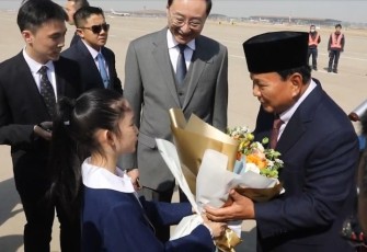 Menhan Prabowo Subianto menerima karangan bunga dari gadis kecil saat tiba di Beijing