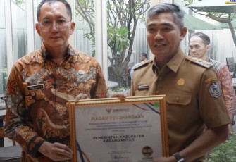 Pj Bupati Karanganyar Timotius Suryadi memegang piagam penghargaan predikat tertinggi kepatuhan penyelenggaraan pelayanan publik tahun 2024 dari Ombudsman Republik Indonesia