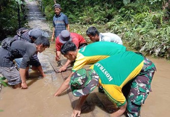 Satgas Pamtas Yonarmed 10 Kostrad saat Bantu Warga Perbatasan Perbaiki Jembatan