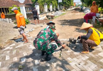 Babinsa Koramil Geneng Bantu Warga Pasang Paving Jalan Desa